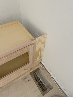 a wooden box sitting on top of a hard wood floor next to a white wall