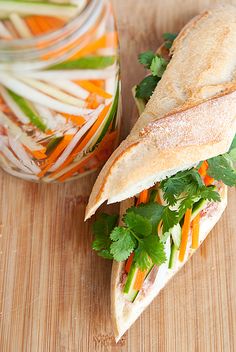 a sandwich with carrots, lettuce and cilantro