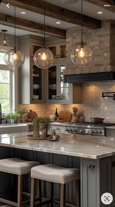 a kitchen with three lights hanging from the ceiling and two stools on the counter