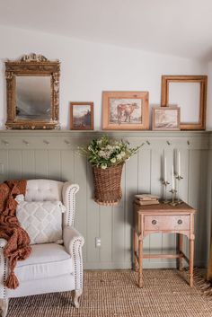 a living room with pictures on the wall and a chair in front of a table