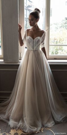 a woman standing in front of a window wearing a dress with sheer sleeves and beading