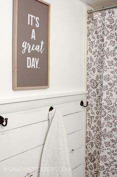 a bathroom with a shower curtain and a sign on the wall above it that says it's a great day