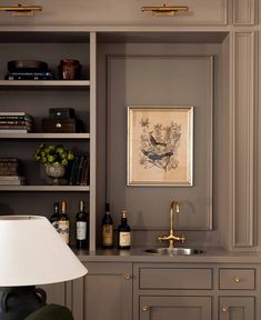 a kitchen with gray cabinets and gold trimmings on the walls, along with a brass faucet