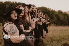 a group of women standing next to each other in a field holding candles and looking at the camera