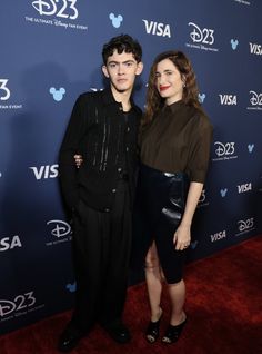 two people standing on a red carpet at an event