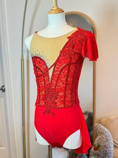 a red leotard with sequins and bows on it is sitting on a mannequin