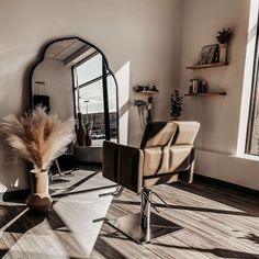 a chair and mirror in a room with wood flooring on the walls, near a large window