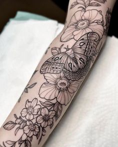 a woman's arm with flowers and a butterfly tattoo on the left side of her arm