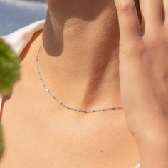 a woman is talking on her cell phone while wearing a necklace with beads and pearls