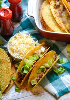 three tacos and two burritos on a checkered table cloth