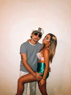 a man and woman are posing for a photo in front of a white wall wearing sailor's hats