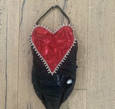 a black bag with a red heart on the front and bottom, sitting on a wooden floor