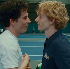 two men standing next to each other on a tennis court