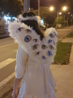 a woman in a white dress with blue eyes on her head walking down the street