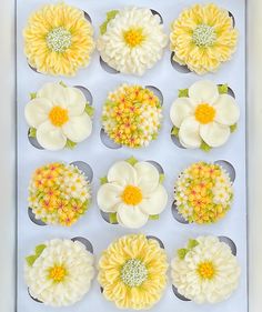 twelve cupcakes with yellow and white flowers in the middle are arranged in a box