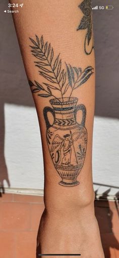 a tattoo on the leg of a person with a vase and plant in it's center