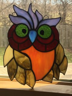 a stained glass owl sitting on top of a window sill