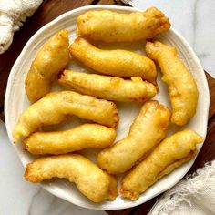 some fried food is on a white plate and sits on a wooden table next to a napkin