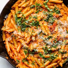 a skillet filled with pasta and sauce covered in parmesan cheese