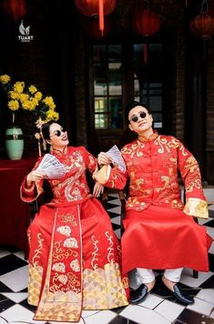 two people dressed in red and gold sitting next to each other