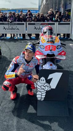 a man sitting on top of a motorcycle next to a sign