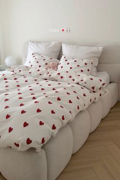 a bed with red hearts on it in a room next to a white wall and window