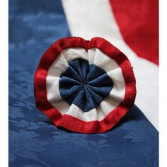 a red, white and blue brooch sitting on top of a bed