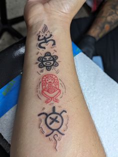 a person's arm with tattoos on it, including an omen and buddha symbols