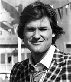 a black and white photo of a man wearing a jacket and tie smiling at the camera