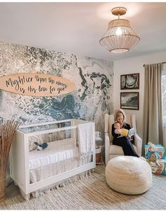 a woman sitting in a chair next to a crib with a baby on it