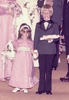 a young boy and girl standing next to each other in front of a group of people