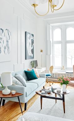 a living room filled with furniture and a chandelier hanging from the ceiling above