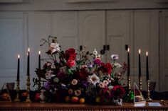 an arrangement of flowers and candles on a table