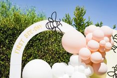 a sign that says first birthday with balloons in the shape of flowers and bees on it