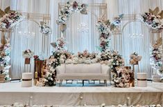 a white couch sitting under a floral covered stage with chandelier and flowers on it