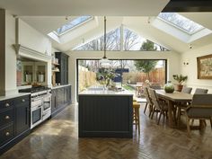 an open kitchen and dining room area with skylights on the roof, hardwood flooring