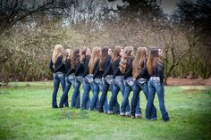 a group of young women standing in a line with their backs turned to the camera