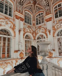 a woman is sitting on a ledge looking up at the ceiling in an ornate building