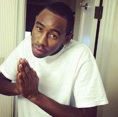 a young man is praying in front of a mirror with his hands folded up and looking at the camera