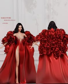 a woman in a red dress with roses on her back, standing next to another model