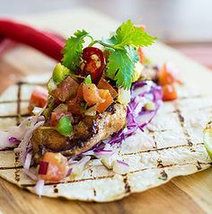 a tortilla topped with meat and vegetables on a cutting board next to a lime