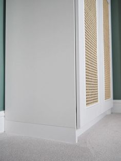 the corner of an empty room with green walls and white trim on the wall,