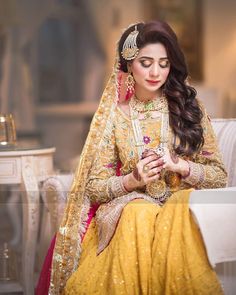 a woman sitting on top of a white couch wearing a yellow and red dress with long hair