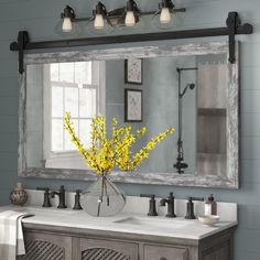 a bathroom vanity with two sinks and a large mirror over the sink that has yellow flowers in it