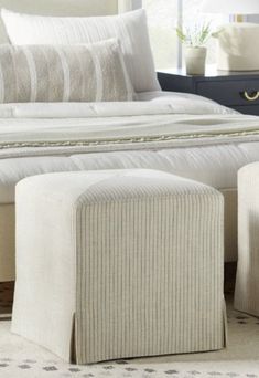 a white bed sitting next to two stools on top of a carpeted floor