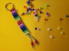 a key chain made out of beads on a yellow surface next to scissors and other items