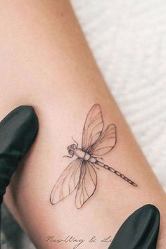 a woman's leg with a tattoo on it that has a dragonfly on it