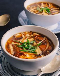 two white bowls filled with soup on top of a blue and white plate