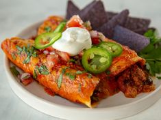 a white plate topped with enchiladas and tortilla chips