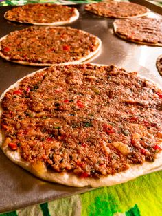 several uncooked pizzas sitting on top of a metal pan covered in toppings